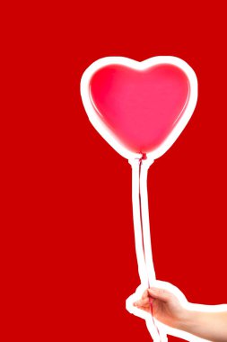 Kadın eli kırmızı kauçuk, şişme kalp şeklinde balon tutuyor. Aşk, ilişki, sevgililer günü ve doğum günü kutlaması konsepti. Boş kopya alanı olan dergi tarzı moda kolajı
