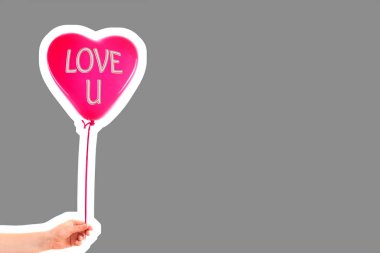 Kadın eli kırmızı kauçuk, şişme kalp şeklinde balon tutuyor. Aşk, ilişki, sevgililer günü ve doğum günü kutlaması konsepti. Boş kopya alanı olan dergi tarzı moda kolajı