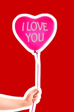 Kadın eli kırmızı kauçuk, şişme kalp şeklinde balon tutuyor. Aşk, ilişki, sevgililer günü ve doğum günü kutlaması konsepti. Boş kopya alanı olan dergi tarzı moda kolajı