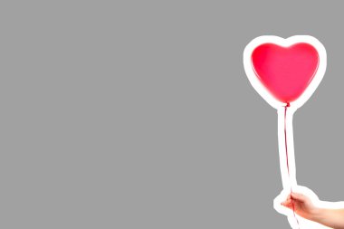 Kadın eli kırmızı kauçuk, şişme kalp şeklinde balon tutuyor. Aşk, ilişki, sevgililer günü ve doğum günü kutlaması konsepti. Boş kopya alanı olan dergi tarzı moda kolajı