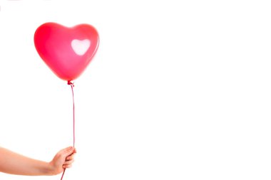 Kadın eli kırmızı kauçuk, şişme kalp şeklinde balon tutuyor. Aşk, ilişki, sevgililer günü ve doğum günü kutlaması konsepti. Stüdyo görüntüsü boş kopya alanı olan bulanık bir arkaplan üzerinde