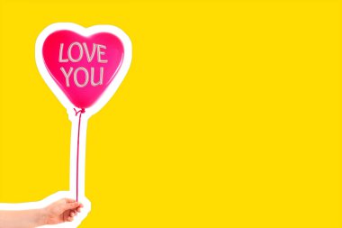 Kadın eli kırmızı kauçuk, şişme kalp şeklinde balon tutuyor. Aşk, ilişki, sevgililer günü ve doğum günü kutlaması konsepti. Boş kopya alanı olan dergi tarzı moda kolajı