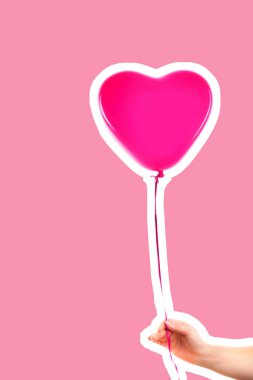 Kadın eli pembe kauçuk, şişme kalp şeklinde balon tutuyor. Aşk, ilişki, sevgililer günü ve doğum günü kutlaması konsepti. Boş kopya alanı olan dergi tarzı moda kolajı