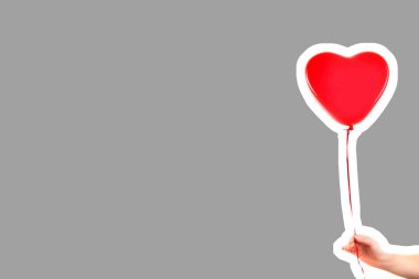 Kadın eli kırmızı kauçuk, şişme kalp şeklinde balon tutuyor. Aşk, ilişki, sevgililer günü ve doğum günü kutlaması konsepti. Boş kopya alanı olan dergi tarzı moda kolajı