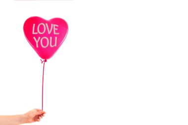 Kadın eli kırmızı kauçuk, şişme kalp şeklinde balon tutuyor. Aşk, ilişki, sevgililer günü ve doğum günü kutlaması konsepti. Stüdyo görüntüsü boş kopya alanı olan bulanık bir arkaplan üzerinde