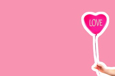 Kadın eli kırmızı kauçuk, şişme kalp şeklinde balon tutuyor. Aşk, ilişki, sevgililer günü ve doğum günü kutlaması konsepti. Boş kopya alanı olan dergi tarzı moda kolajı