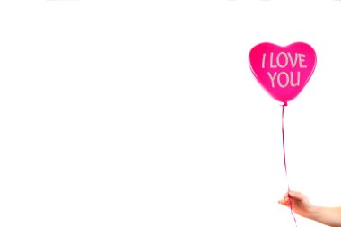 Kadın eli kırmızı kauçuk, şişme kalp şeklinde balon tutuyor. Aşk, ilişki, sevgililer günü ve doğum günü kutlaması konsepti. Stüdyo görüntüsü boş kopya alanı olan bulanık bir arkaplan üzerinde