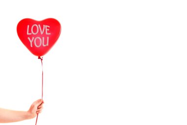 Kadın eli kırmızı kauçuk, şişme kalp şeklinde balon tutuyor. Aşk, ilişki, sevgililer günü ve doğum günü kutlaması konsepti. Stüdyo görüntüsü boş kopya alanı olan bulanık bir arkaplan üzerinde