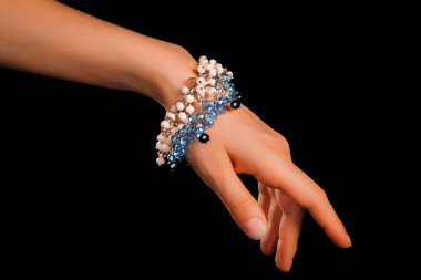 Güzel bir el yapımı mücevher bileziği. Renkli parlak boncuklar ve nötr manikürlü gevşek bir kadın bileği. Moda ve el işi aksesuarları. Yumuşak seçici odaklı yakın plan