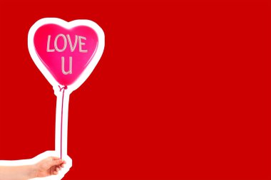 Kadın eli kırmızı kauçuk, şişme kalp şeklinde balon tutuyor. Aşk, ilişki, sevgililer günü ve doğum günü kutlaması konsepti. Boş kopya alanı olan dergi tarzı moda kolajı