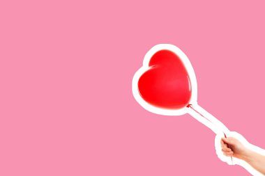 Kadın eli kırmızı kauçuk, şişme kalp şeklinde balon tutuyor. Aşk, ilişki, sevgililer günü ve doğum günü kutlaması konsepti. Boş kopya alanı olan dergi tarzı moda kolajı