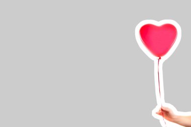 Kadın eli kırmızı kauçuk, şişme kalp şeklinde balon tutuyor. Aşk, ilişki, sevgililer günü ve doğum günü kutlaması konsepti. Boş kopya alanı olan dergi tarzı moda kolajı