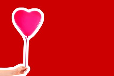 Kadın eli pembe kauçuk, şişme kalp şeklinde balon tutuyor. Aşk, ilişki, sevgililer günü ve doğum günü kutlaması konsepti. Boş kopya alanı olan dergi tarzı moda kolajı