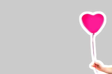 Kadın eli pembe kauçuk, şişme kalp şeklinde balon tutuyor. Aşk, ilişki, sevgililer günü ve doğum günü kutlaması konsepti. Boş kopya alanı olan dergi tarzı moda kolajı