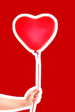 Kadın eli kırmızı kauçuk, şişme kalp şeklinde balon tutuyor. Aşk, ilişki, sevgililer günü ve doğum günü kutlaması konsepti. Boş kopya alanı olan dergi tarzı moda kolajı