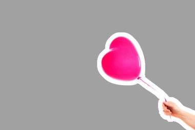 Kadın eli pembe kauçuk, şişme kalp şeklinde balon tutuyor. Aşk, ilişki, sevgililer günü ve doğum günü kutlaması konsepti. Boş kopya alanı olan dergi tarzı moda kolajı