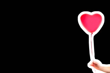 Kadın eli kırmızı kauçuk, şişme kalp şeklinde balon tutuyor. Aşk, ilişki, sevgililer günü ve doğum günü kutlaması konsepti. Boş kopya alanı olan dergi tarzı moda kolajı