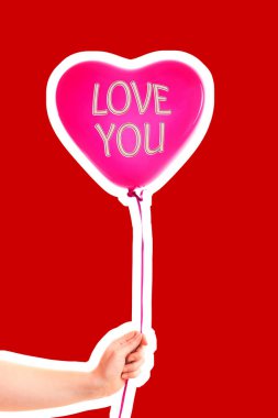 Kadın eli kırmızı kauçuk, şişme kalp şeklinde balon tutuyor. Aşk, ilişki, sevgililer günü ve doğum günü kutlaması konsepti. Boş kopya alanı olan dergi tarzı moda kolajı