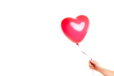 Kadın eli kırmızı kauçuk, şişme kalp şeklinde balon tutuyor. Aşk, ilişki, sevgililer günü ve doğum günü kutlaması konsepti. Stüdyo görüntüsü boş kopya alanı olan bulanık bir arkaplan üzerinde