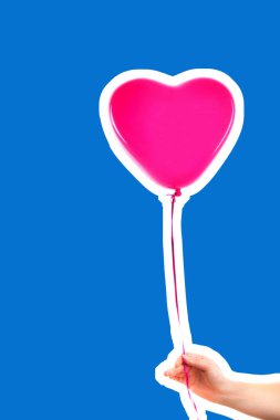 Kadın eli pembe kauçuk, şişme kalp şeklinde balon tutuyor. Aşk, ilişki, sevgililer günü ve doğum günü kutlaması konsepti. Boş kopya alanı olan dergi tarzı moda kolajı
