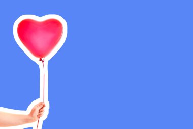 Kadın eli kırmızı kauçuk, şişme kalp şeklinde balon tutuyor. Aşk, ilişki, sevgililer günü ve doğum günü kutlaması konsepti. Boş kopya alanı olan dergi tarzı moda kolajı