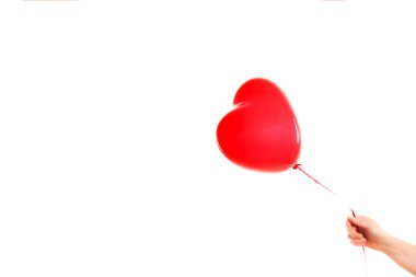 Kadın eli kırmızı kauçuk, şişme kalp şeklinde balon tutuyor. Aşk, ilişki, sevgililer günü ve doğum günü kutlaması konsepti. Stüdyo görüntüsü boş kopya alanı olan bulanık bir arkaplan üzerinde