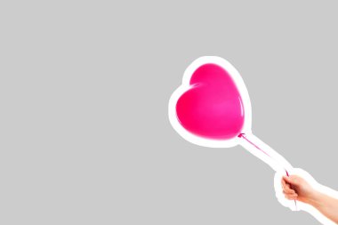 Kadın eli pembe kauçuk, şişme kalp şeklinde balon tutuyor. Aşk, ilişki, sevgililer günü ve doğum günü kutlaması konsepti. Boş kopya alanı olan dergi tarzı moda kolajı