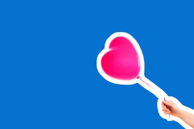 Kadın eli pembe kauçuk, şişme kalp şeklinde balon tutuyor. Aşk, ilişki, sevgililer günü ve doğum günü kutlaması konsepti. Boş kopya alanı olan dergi tarzı moda kolajı