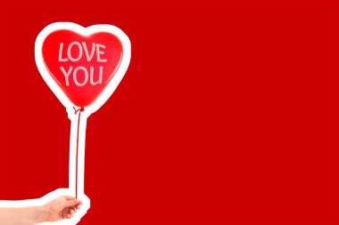 Kadın eli kırmızı kauçuk, şişme kalp şeklinde balon tutuyor. Aşk, ilişki, sevgililer günü ve doğum günü kutlaması konsepti. Boş kopya alanı olan dergi tarzı moda kolajı