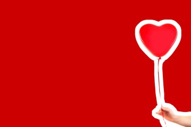 Kadın eli kırmızı kauçuk, şişme kalp şeklinde balon tutuyor. Aşk, ilişki, sevgililer günü ve doğum günü kutlaması konsepti. Boş kopya alanı olan dergi tarzı moda kolajı