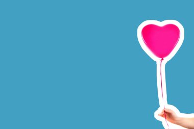 Kadın eli pembe kauçuk, şişme kalp şeklinde balon tutuyor. Aşk, ilişki, sevgililer günü ve doğum günü kutlaması konsepti. Boş kopya alanı olan dergi tarzı moda kolajı
