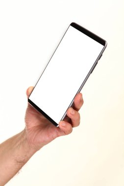 İnsan eli, avucunda boş bir krom ekran olan modern bir akıllı telefonu tutar. Teknoloji ve reklam kavramı. Ayrıntılı yakın çekim stüdyo çekimi soyut beyaz arka planda izole