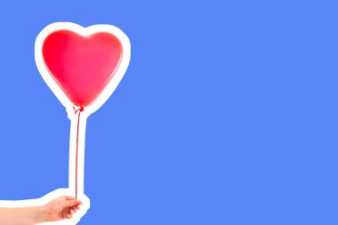 Kadın eli kırmızı kauçuk, şişme kalp şeklinde balon tutuyor. Aşk, ilişki, sevgililer günü ve doğum günü kutlaması konsepti. Boş kopya alanı olan dergi tarzı moda kolajı