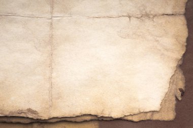 Aged paper sheet. Blank old background with dust and dirty stains. Vintage and antique art concept. Poster mockup. Detailed closeup studio shot. Front view. Toned