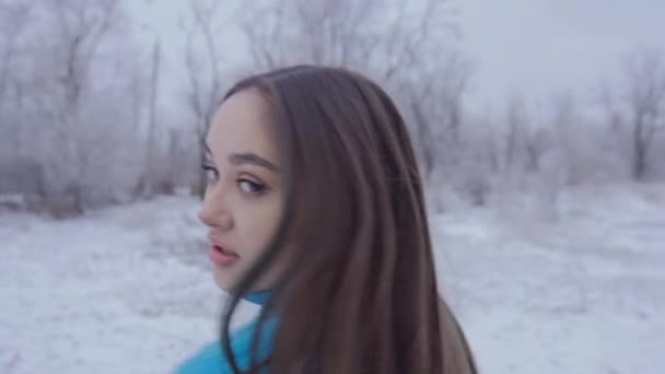 Schönes nettes Mädchen mit langen Haaren posiert im Winterwald. — Stockvideo