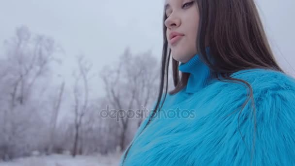 Schönes nettes Mädchen mit langen Haaren posiert im Winterwald. — Stockvideo