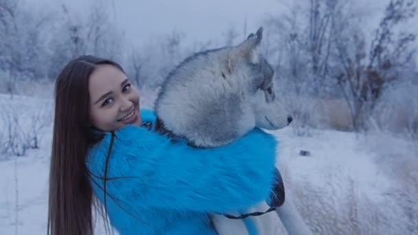 Schönes Mädchen umarmt einen Husky-Hund. — Stockvideo