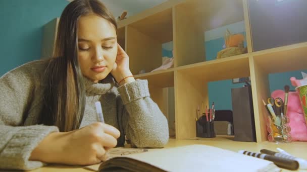 Uma jovem com cabelo comprido desenha um feltro-basculante à noite no álbum . — Vídeo de Stock