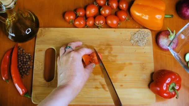 Une femme coupe une tomate cerise avec un couteau de cuisine . — Video