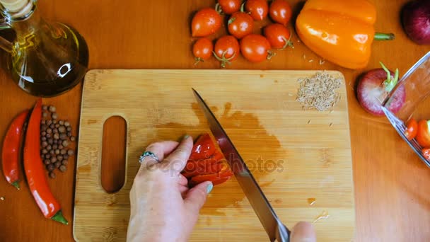 Une femme coupe un poivron rouge . — Video