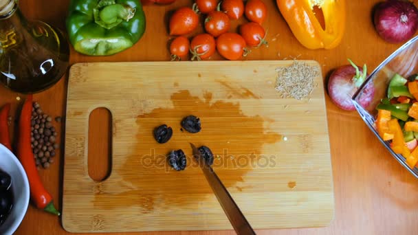 Eine Frau schneidet schwarze Oliven. — Stockvideo