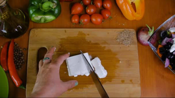 Una mujer está cortando queso blanco Feta . — Vídeo de stock