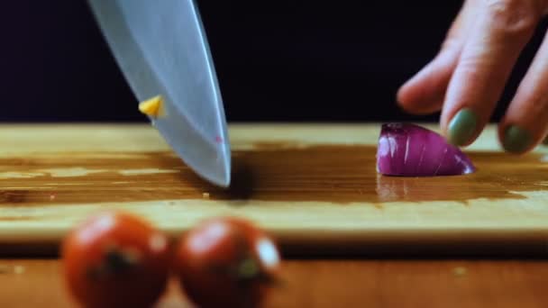 Una mujer corta una cebolla con un cuchillo de cocina . — Vídeos de Stock