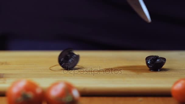 Une femme coupe des olives noires avec un couteau de cuisine. Mouvement lent . — Video