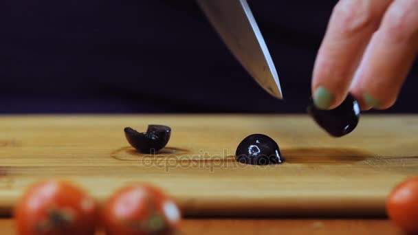 Una mujer corta aceitunas negras con un cuchillo de cocina . — Vídeos de Stock