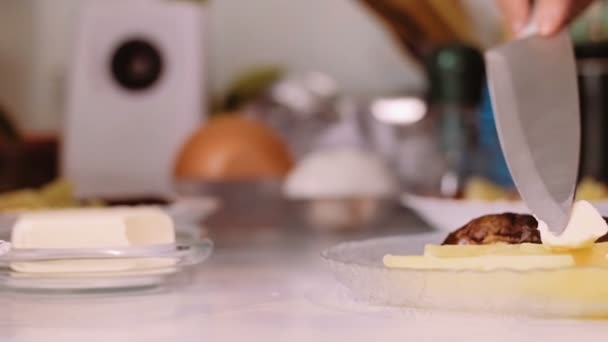 Una mujer con un cuchillo pone mantequilla en un plato con comida . — Vídeo de stock