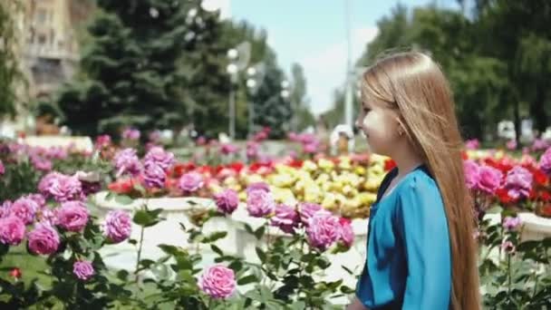 Девушка с длинными волосами в синем платье идет по городскому парку . — стоковое видео