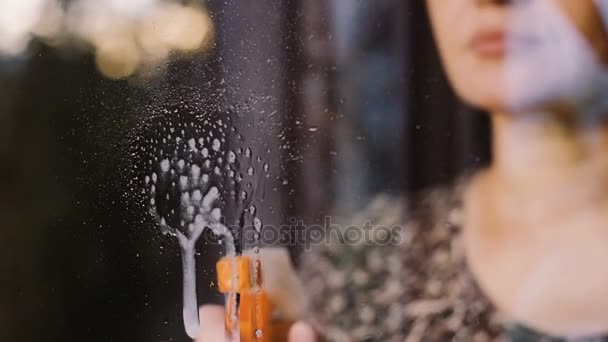 A woman washes a window in the rays of the setting sun. — Stock Video