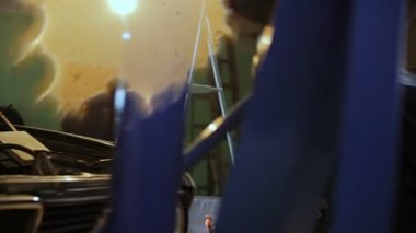 Motorlu arabalar hood dışarı çekmek için küçük bir vinç Oto mekaniği kullanın.