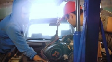 İki araba tamircisi ile araba motor bir küçük vinç çekin.